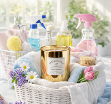 Load image into Gallery viewer, Basket with cleaning supplies, a candle, and flowers on a light background